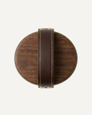 Wooden coaster with leather strap on a white background