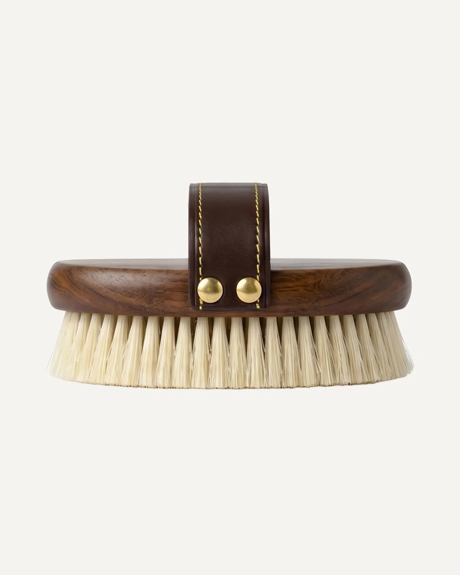 Brush with wooden handle and brown leather strap on a white background